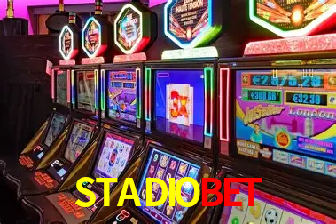 Una escena digital vívida inspirada en casino con STADIOBET mostrado prominentemente, luces brillantes, fichas, cartas y acentos dorados.